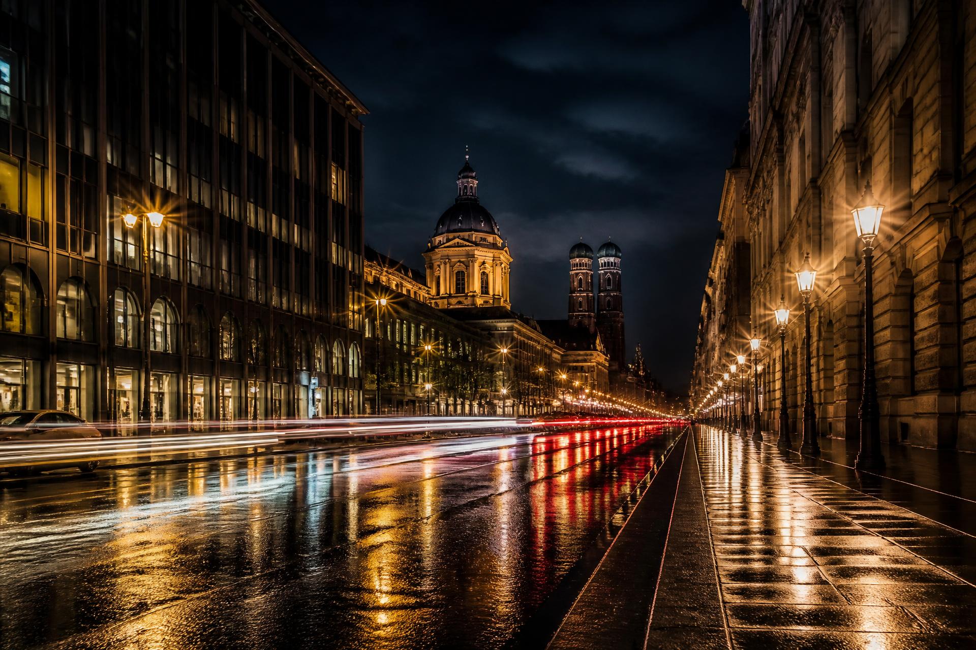 Münchner Boulevard bei Nacht mit Straßenlaternen und Lichtreflexen